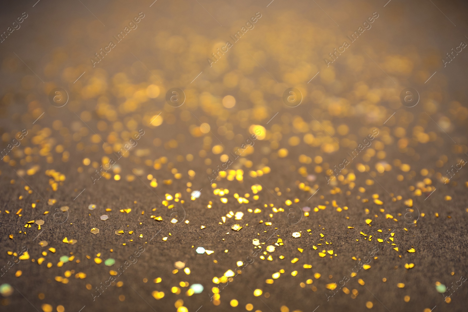 Photo of Shiny golden glitter on grey background. Bokeh effect