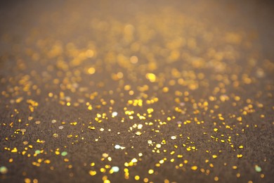 Photo of Shiny golden glitter on grey background. Bokeh effect