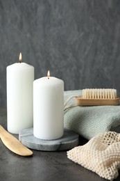 Composition with different spa products and burning candles on grey table