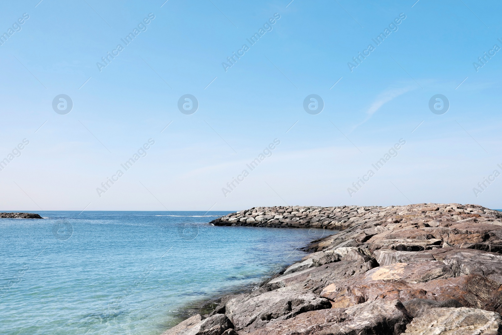 Photo of Picturesque view of beach with stone breakwater on sunny day