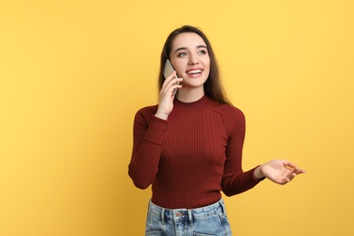 Photo of Young woman talking on phone against color background