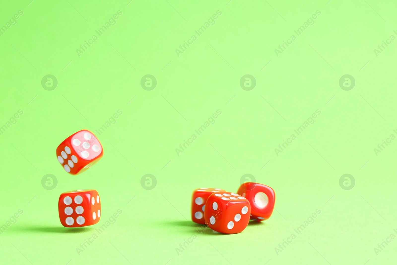 Photo of Many red game dices falling on green background. Space for text