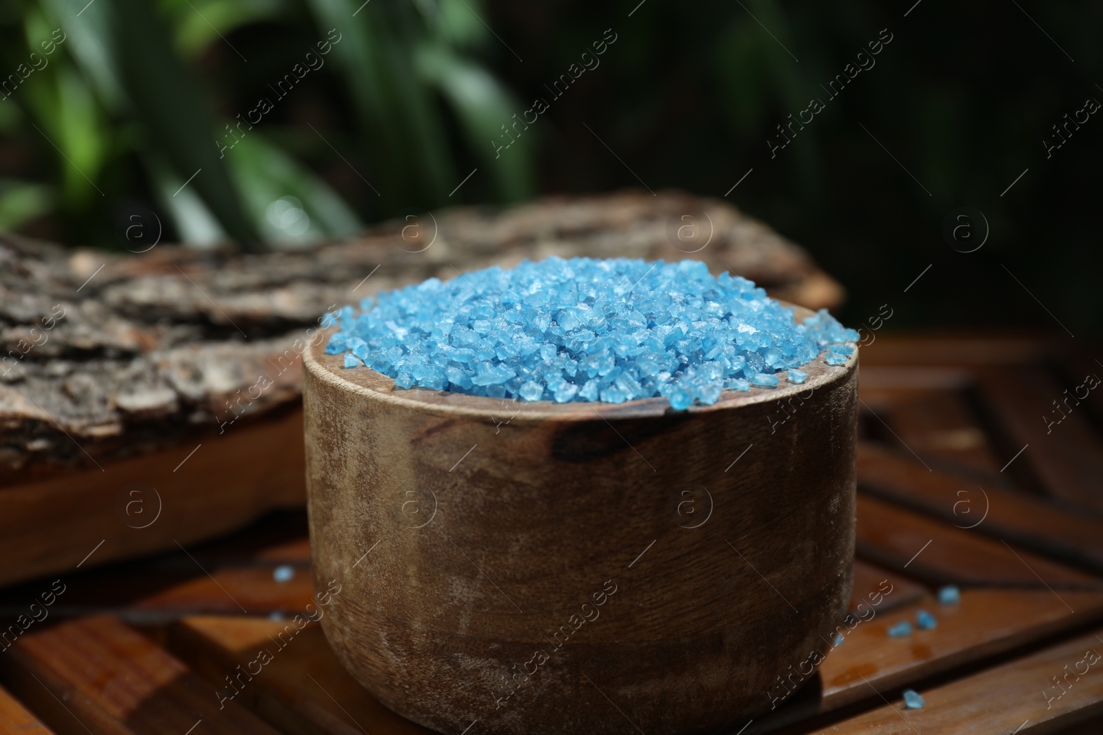 Photo of Bowl of blue sea salt on wooden table, closeup