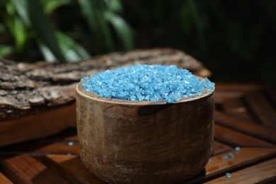 Bowl of blue sea salt on wooden table, closeup