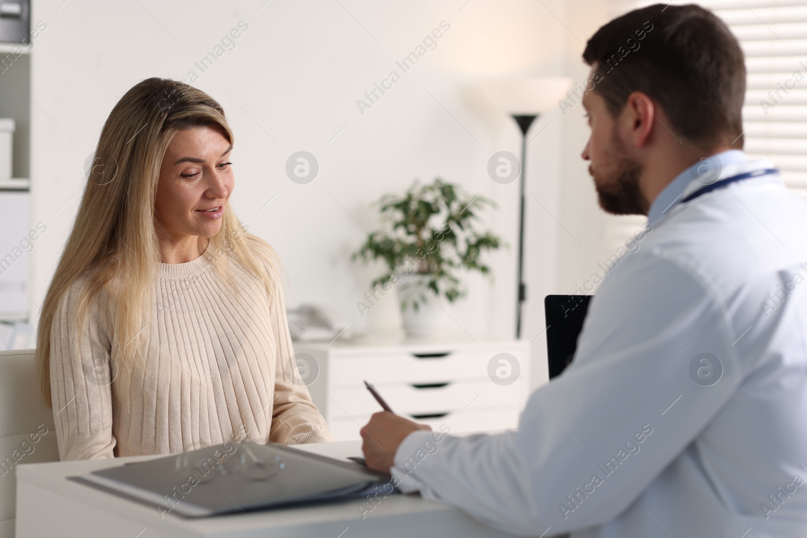 Photo of Professional doctor working with patient at white table in hospital