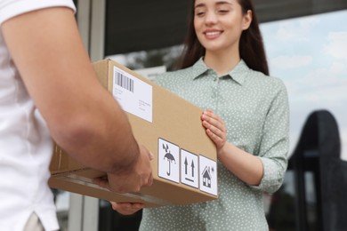 Woman receiving parcel from courier outdoors, closeup
