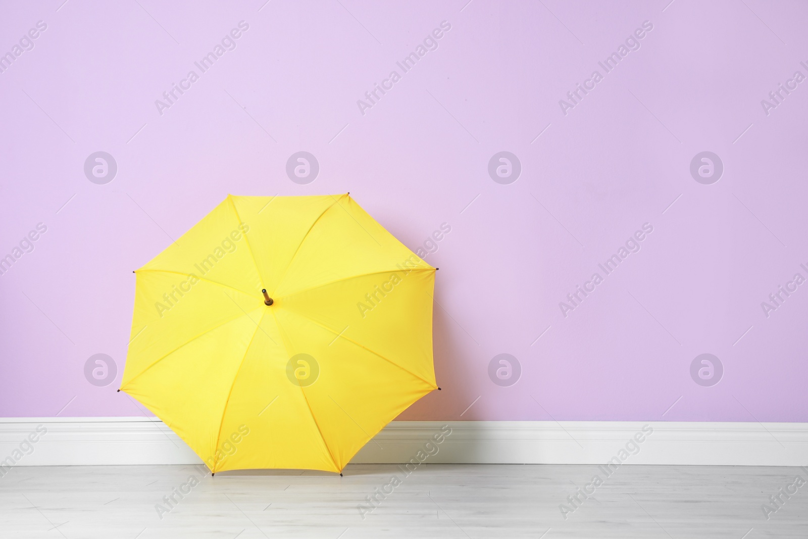 Photo of Beautiful open umbrella on floor near color wall with space for design