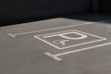 Image of Car parking lot with white marking lines and wheelchair symbol outdoors