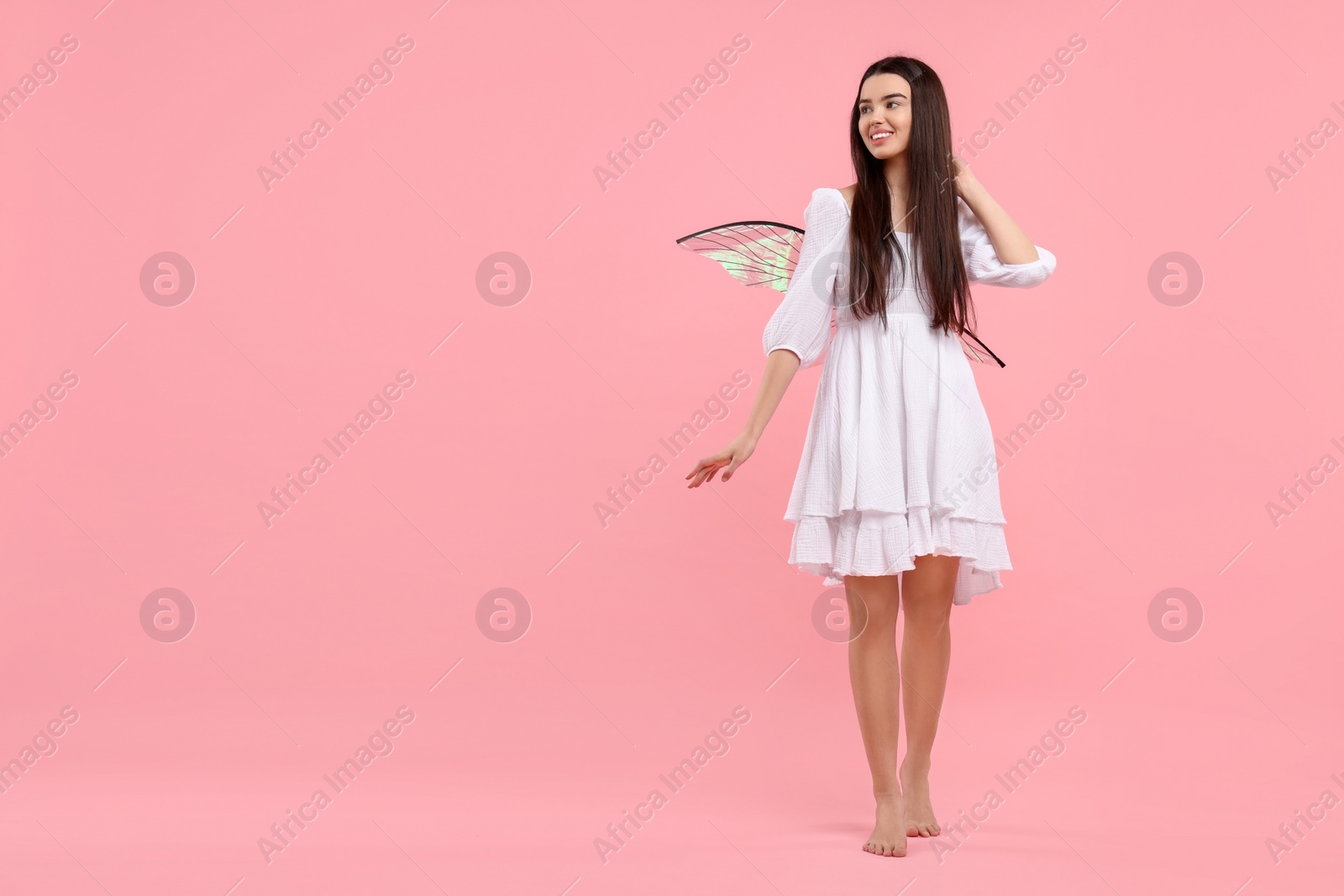 Photo of Beautiful girl in fairy costume with wings on pink background, space for text