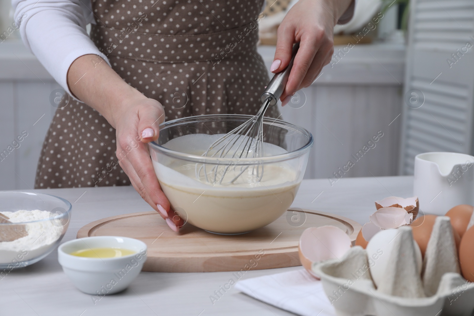 Photo of Woman making dough with whisk in bowl at table, closeup