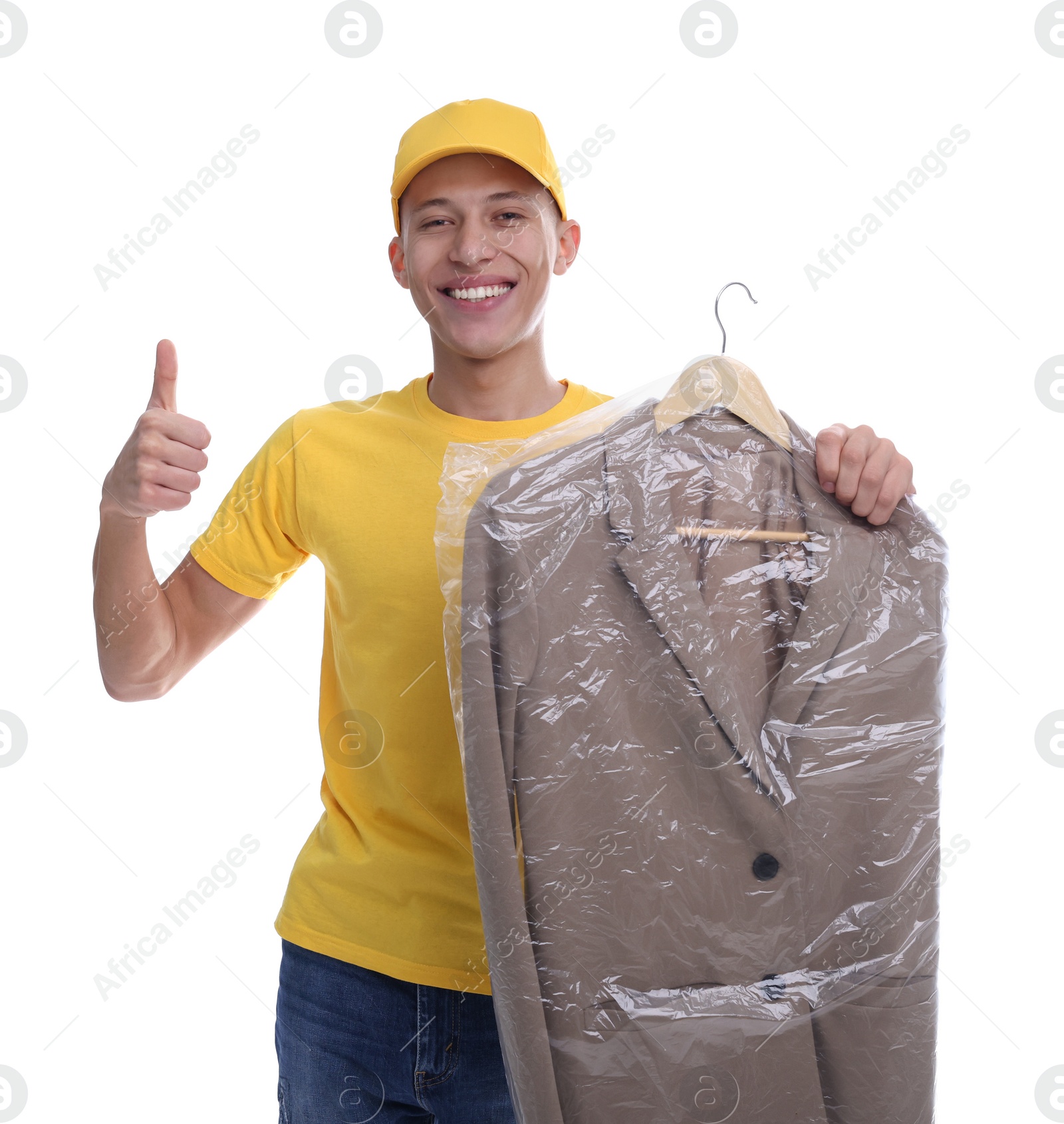 Photo of Dry-cleaning delivery. Happy courier holding jacket in plastic bag and showing thumbs up on white background