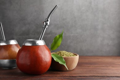 Photo of Calabash with mate tea and bombilla on wooden table. Space for text