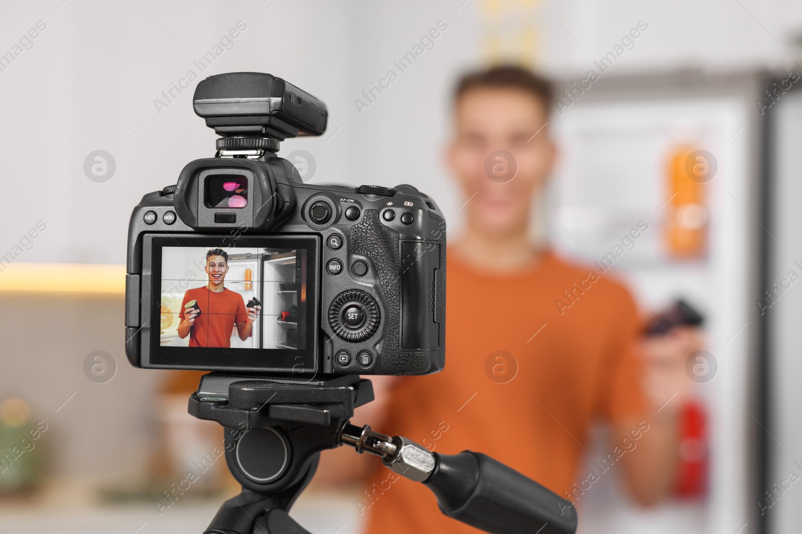 Photo of Food blogger recording video in kitchen, focus on camera