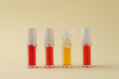 Photo of Bright lip glosses and flower on beige background