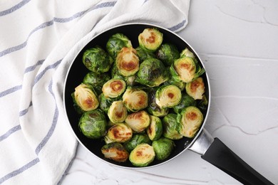 Photo of Delicious roasted Brussels sprouts in frying pan on white textured table, top view
