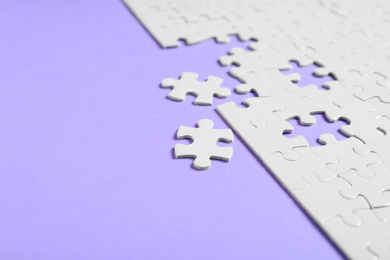 Photo of Blank white puzzle pieces on violet background