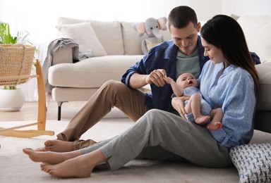 Photo of Happy family with cute baby near sofa at home