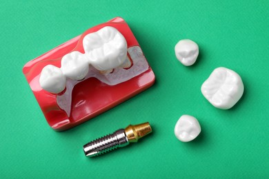 Photo of Educational model of gum with teeth, post and crown for dental implant on green background, flat lay