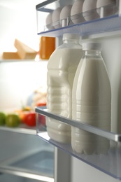 Gallon and bottle of milk in refrigerator, closeup