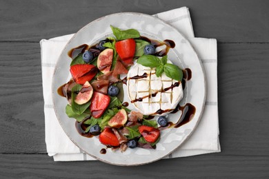 Photo of Delicious salad with brie cheese, prosciutto, berries and balsamic vinegar on grey wooden table, top view