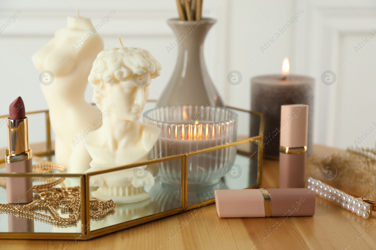 Photo of David bust and female body shaped candles on wooden table. Stylish decor