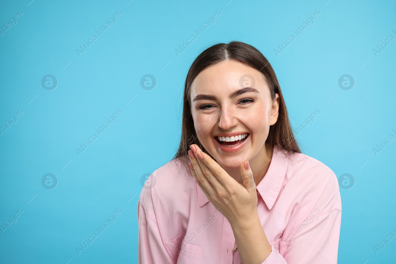 Photo of Beautiful woman laughing on light blue background. Space for text