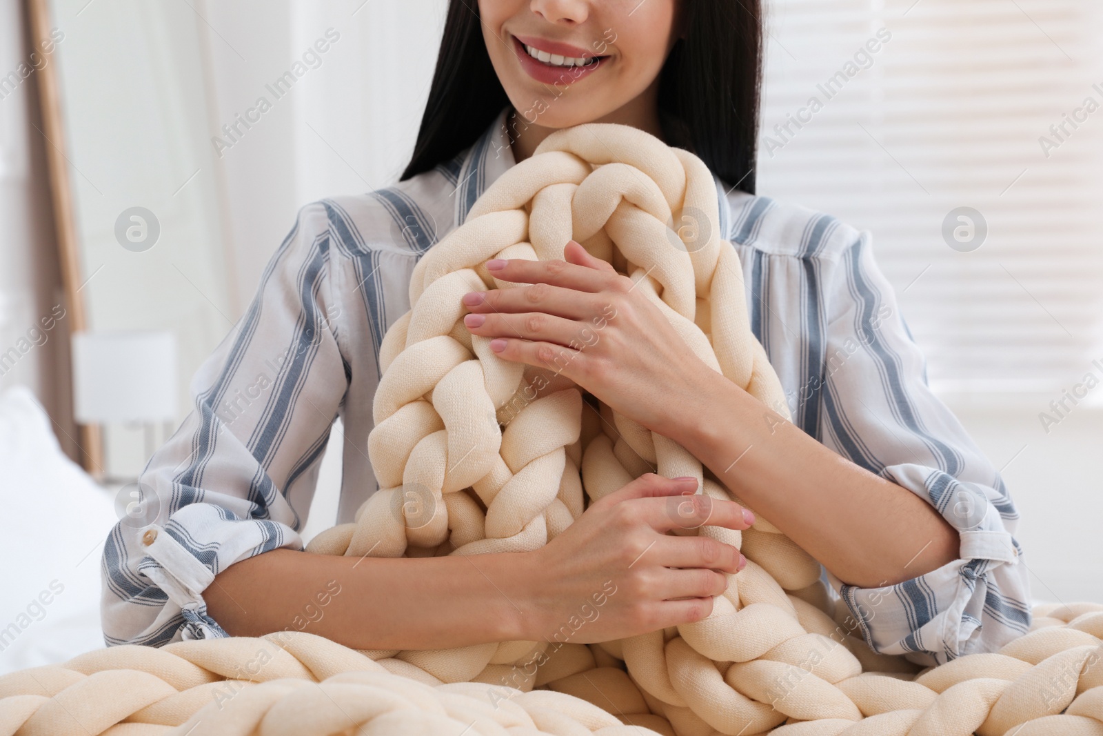 Photo of Woman with chunky knit blanket at home, closeup