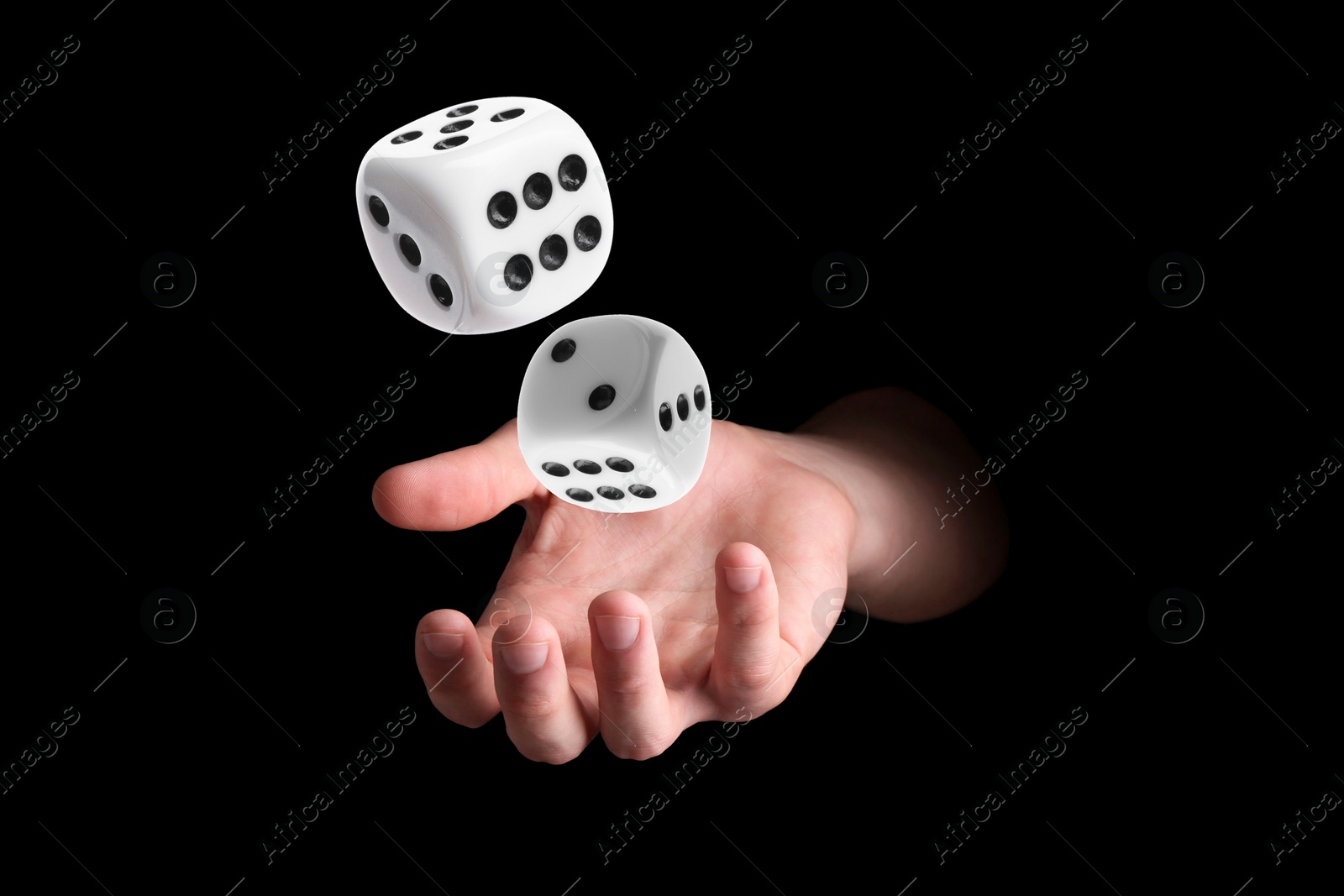 Image of Man throwing white dice on black background, closeup