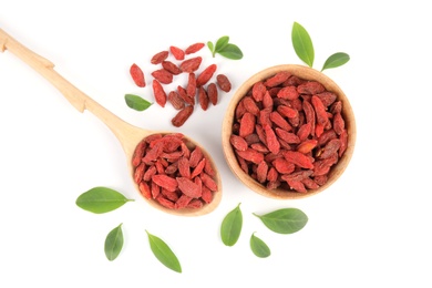 Photo of Wooden bowl and spoon of dried goji berries with leaves on white background, top view