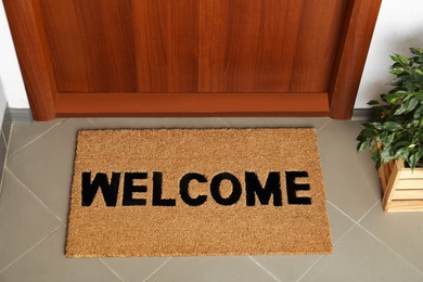 Photo of Door mat with word Welcome on floor near entrance, above view