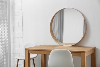 Photo of Makeup room interior with wooden table and mirror near white wall