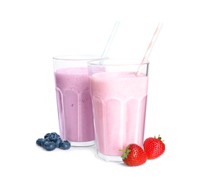 Different tasty milk shakes and berries isolated on white