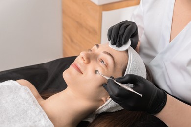 Cosmetologist using scrubber, closeup. Client having cleansing procedure