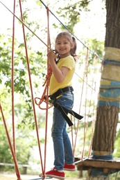 Photo of Little girl climbing in adventure park. Summer camp