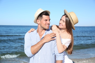 Lovely couple wearing hats together on beach