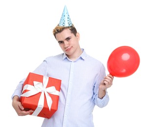 Sad young man with party hat, gift box and balloon on white background