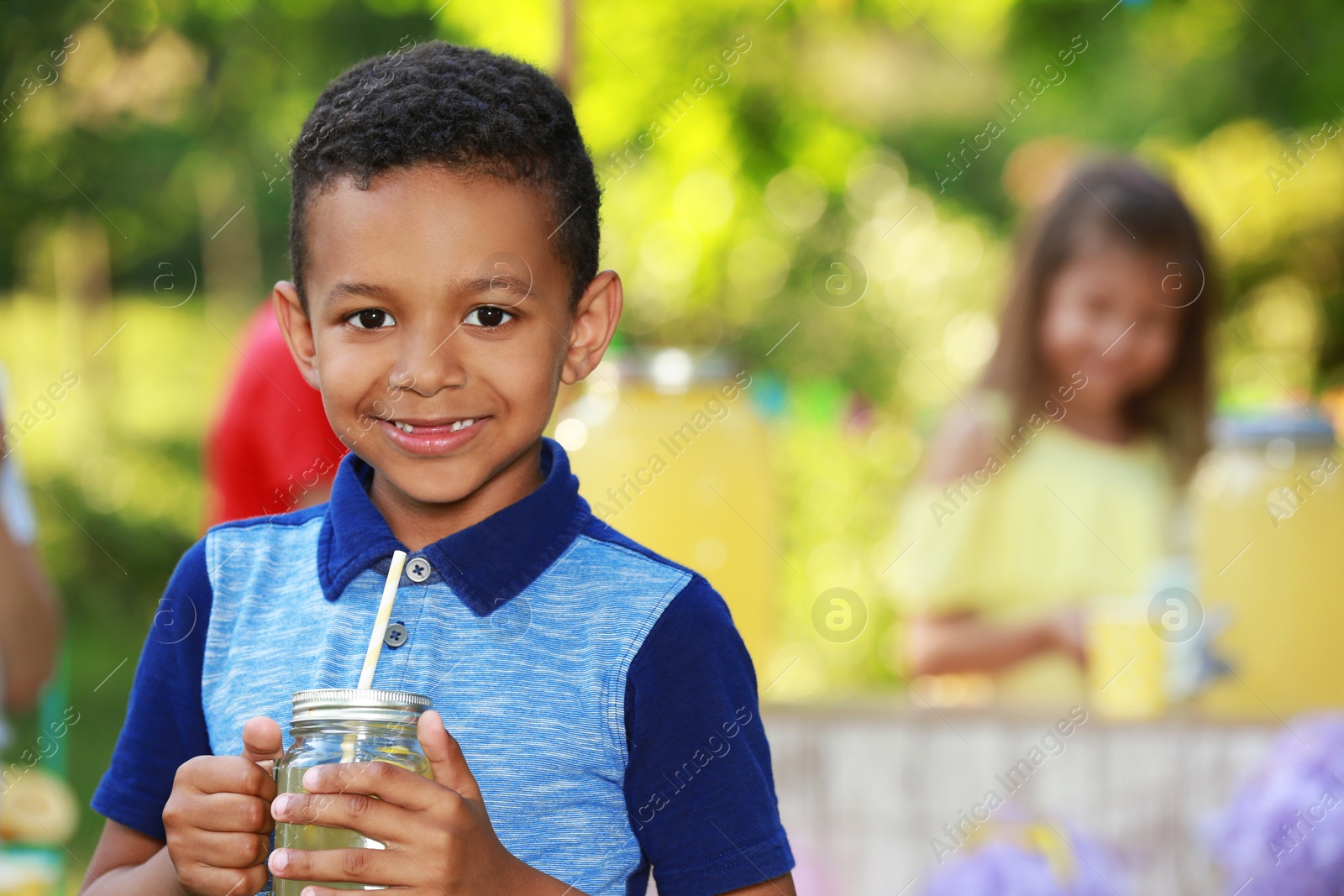 Photo of Cute little African-American boy with natural lemonade in park, space for text. Summer refreshing drink