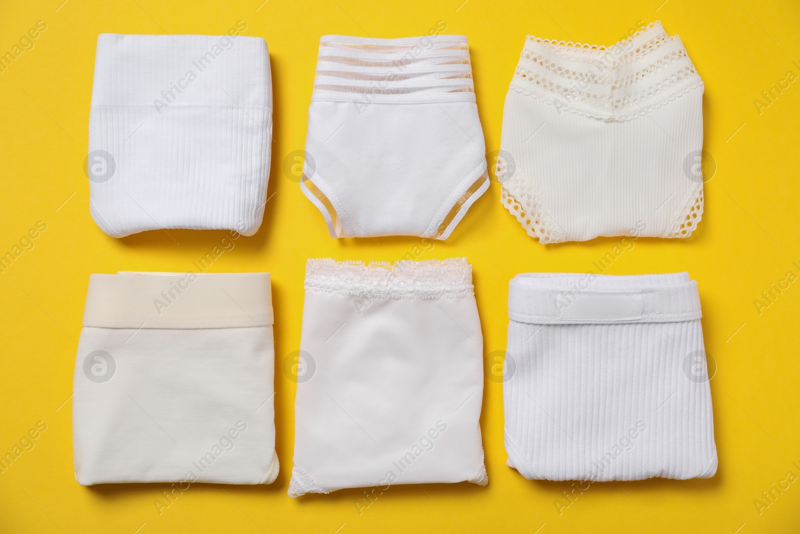 Photo of Stylish folded women's underwear on yellow background, flat lay