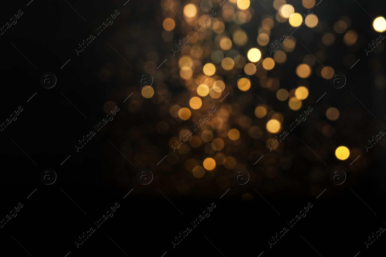 Photo of Blurred view of golden lights on black background. Bokeh effect