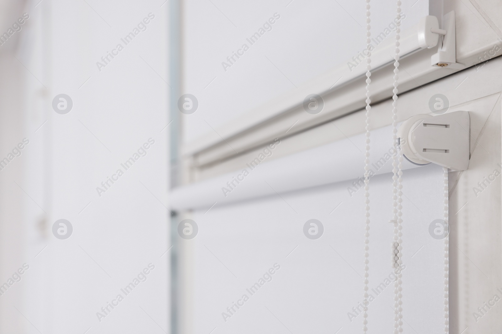 Photo of Window with white roller blinds, closeup view