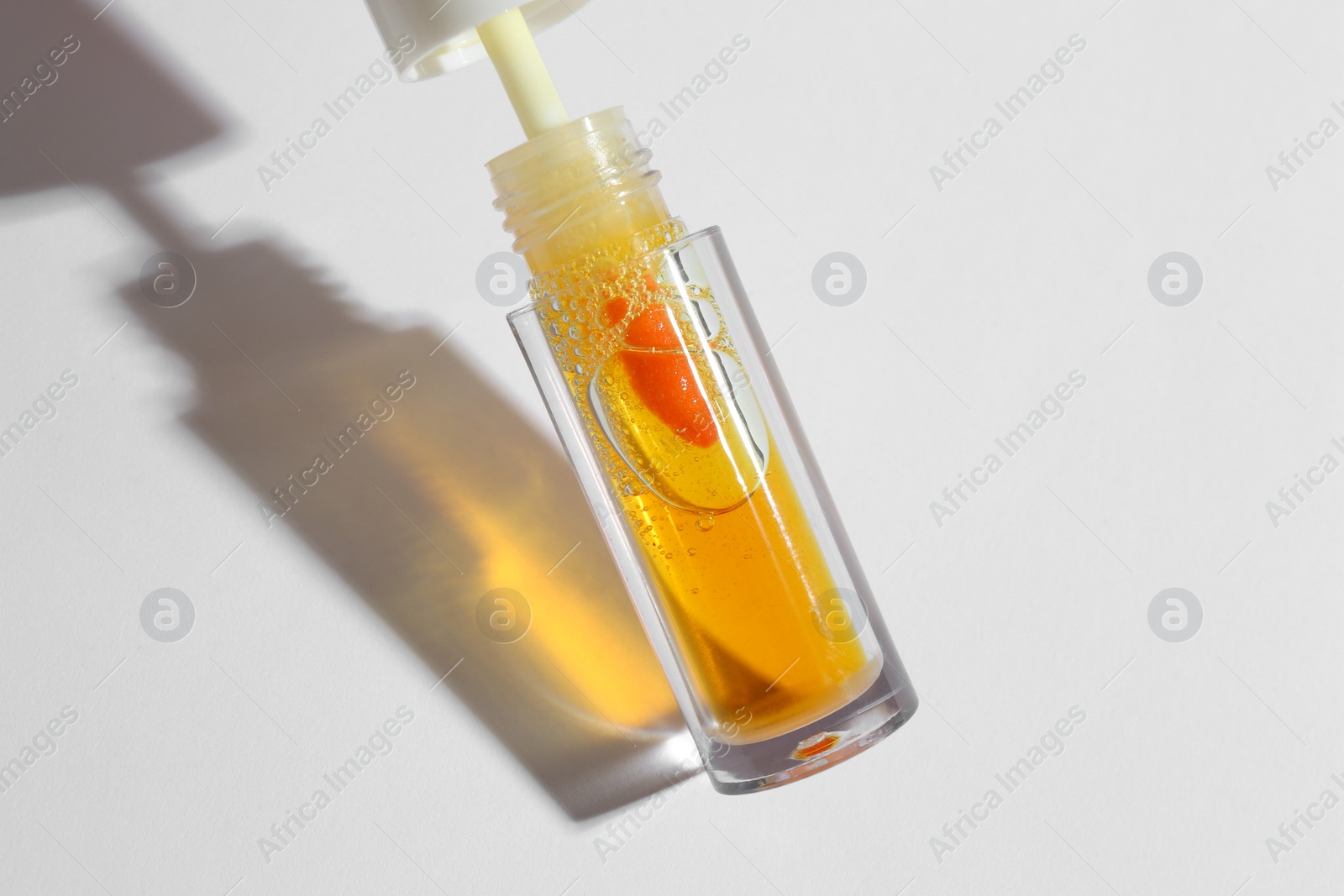 Photo of Orange lip gloss on white background, closeup