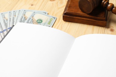 Tax law. Notebook, dollar banknotes and gavel on wooden table, closeup