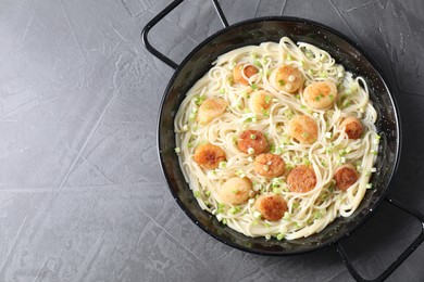 Photo of Delicious scallop pasta with green onion on grey table, top view. Space for text