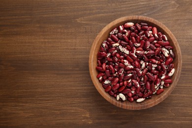 Bowl with dry kidney beans on wooden table, top view. Space for text