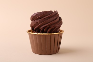 Delicious chocolate cupcake on beige background, closeup