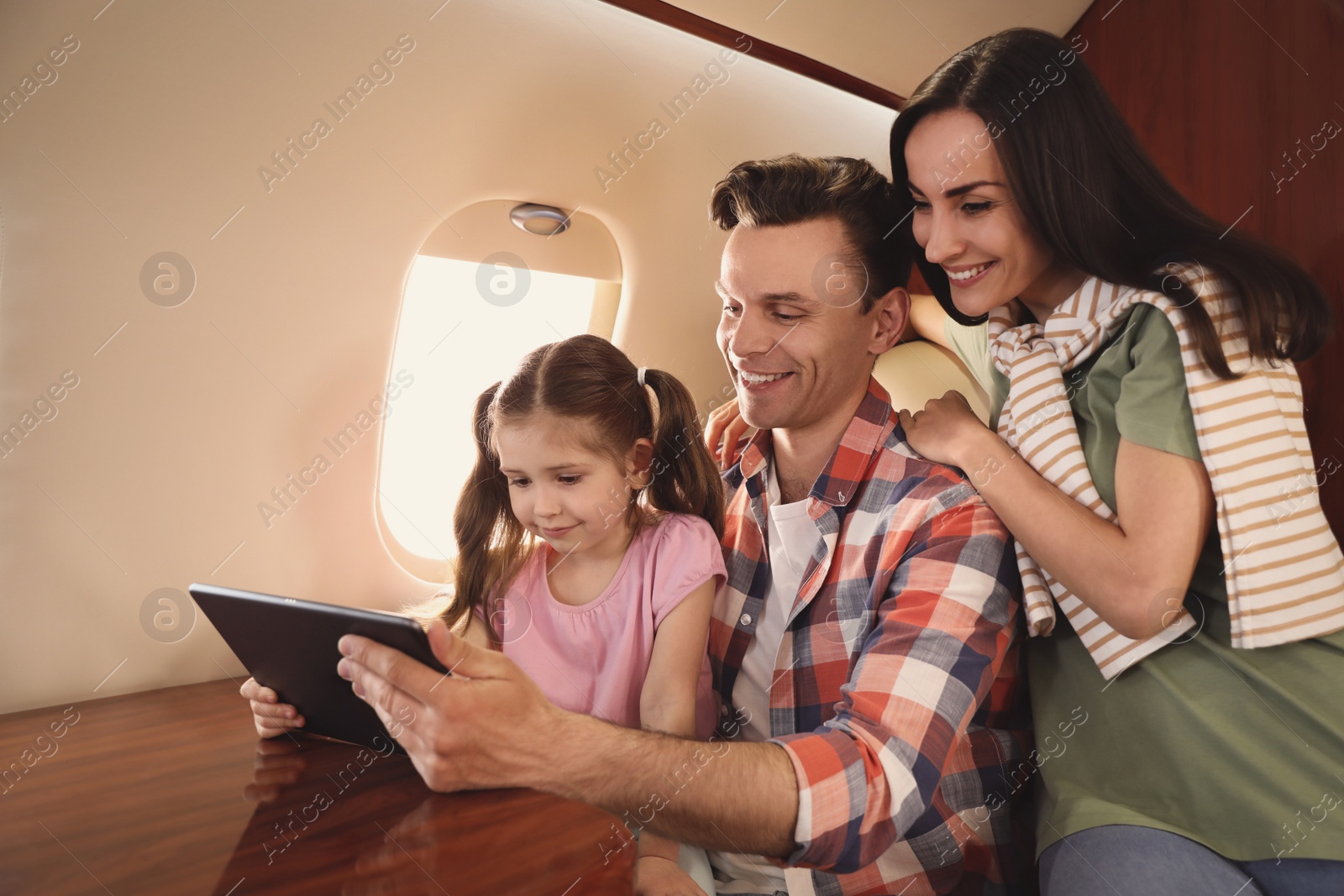 Photo of Happy family using tablet in airplane during flight