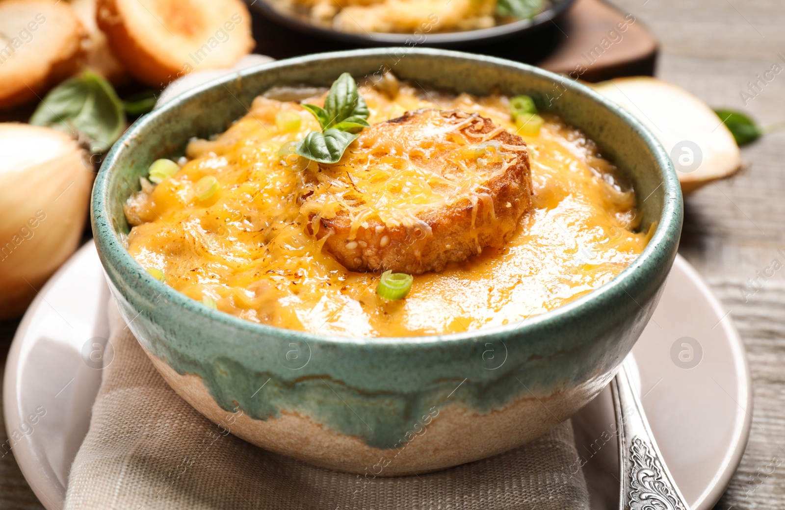 Photo of Tasty homemade French onion soup on wooden table, closeup