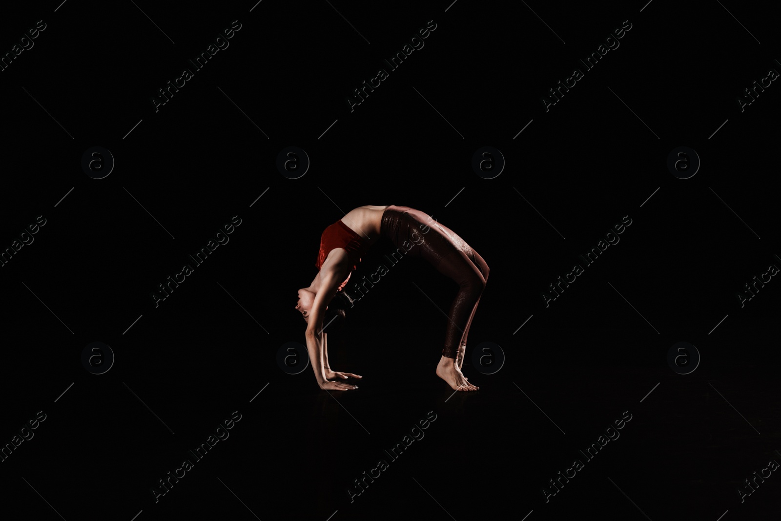 Photo of Young woman performing acrobatic element on stage indoors