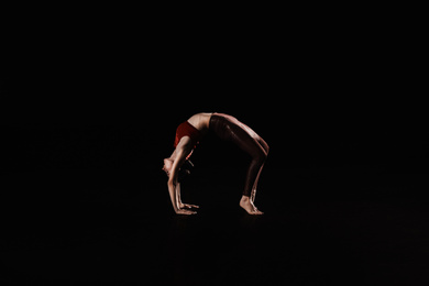 Photo of Young woman performing acrobatic element on stage indoors