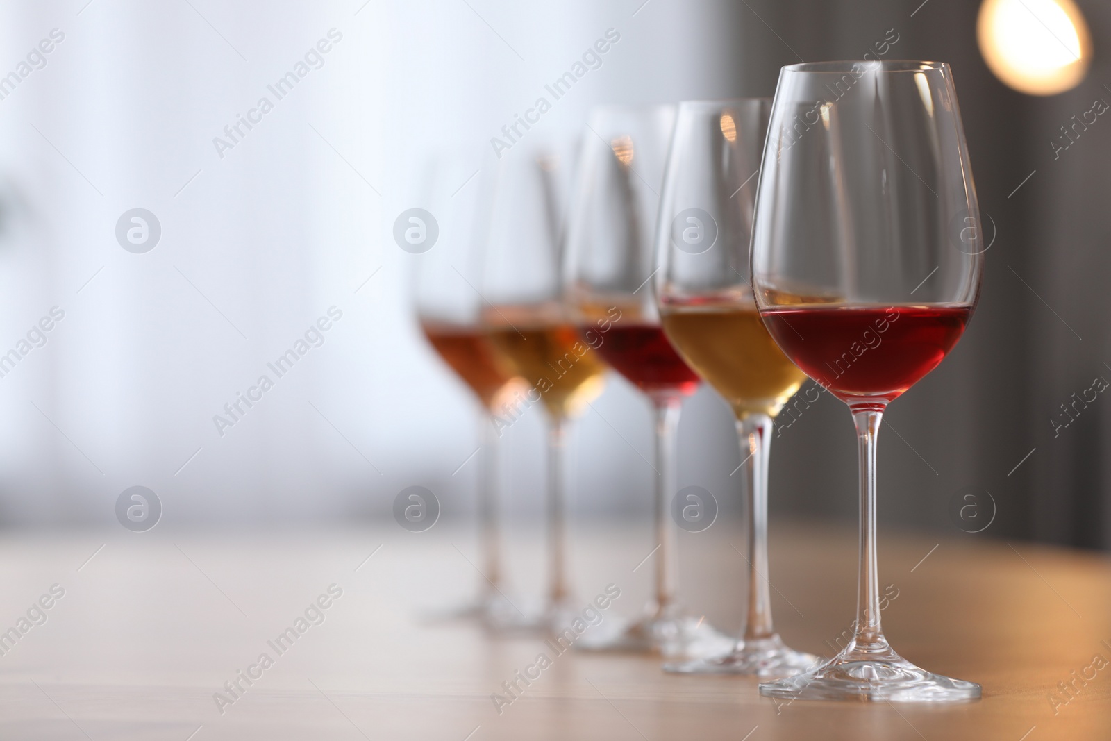 Photo of Different sorts of wine in glasses on wooden table indoors. Space for text